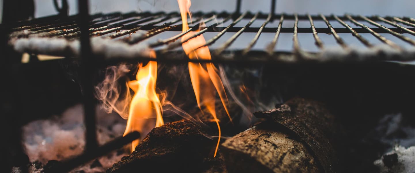 Leños de encino ardiendo bajo una parrilla de hierro