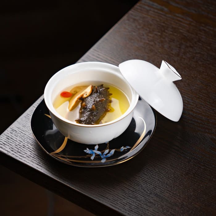 Caldo claro con hongos en tazón de porcelana sobre una mesa de madera oscura