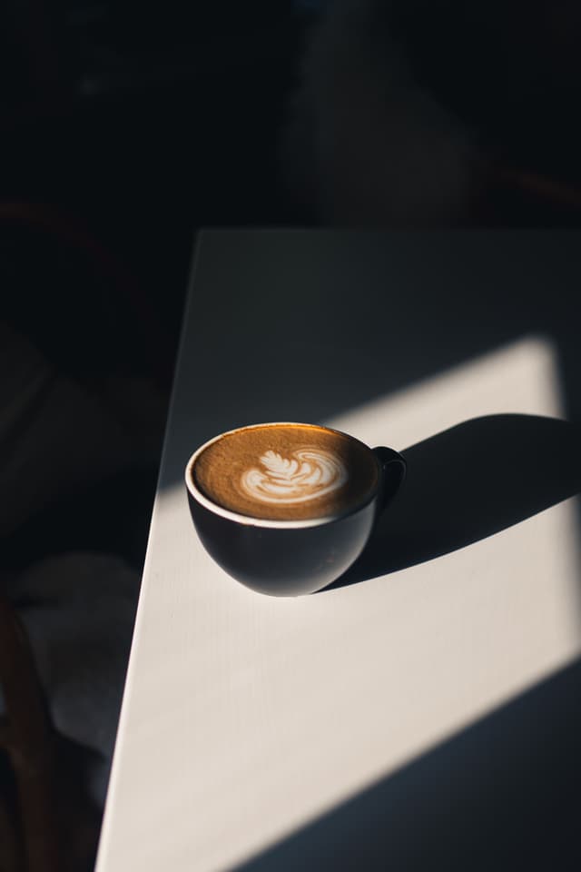 Latte con arte en espuma en taza negra